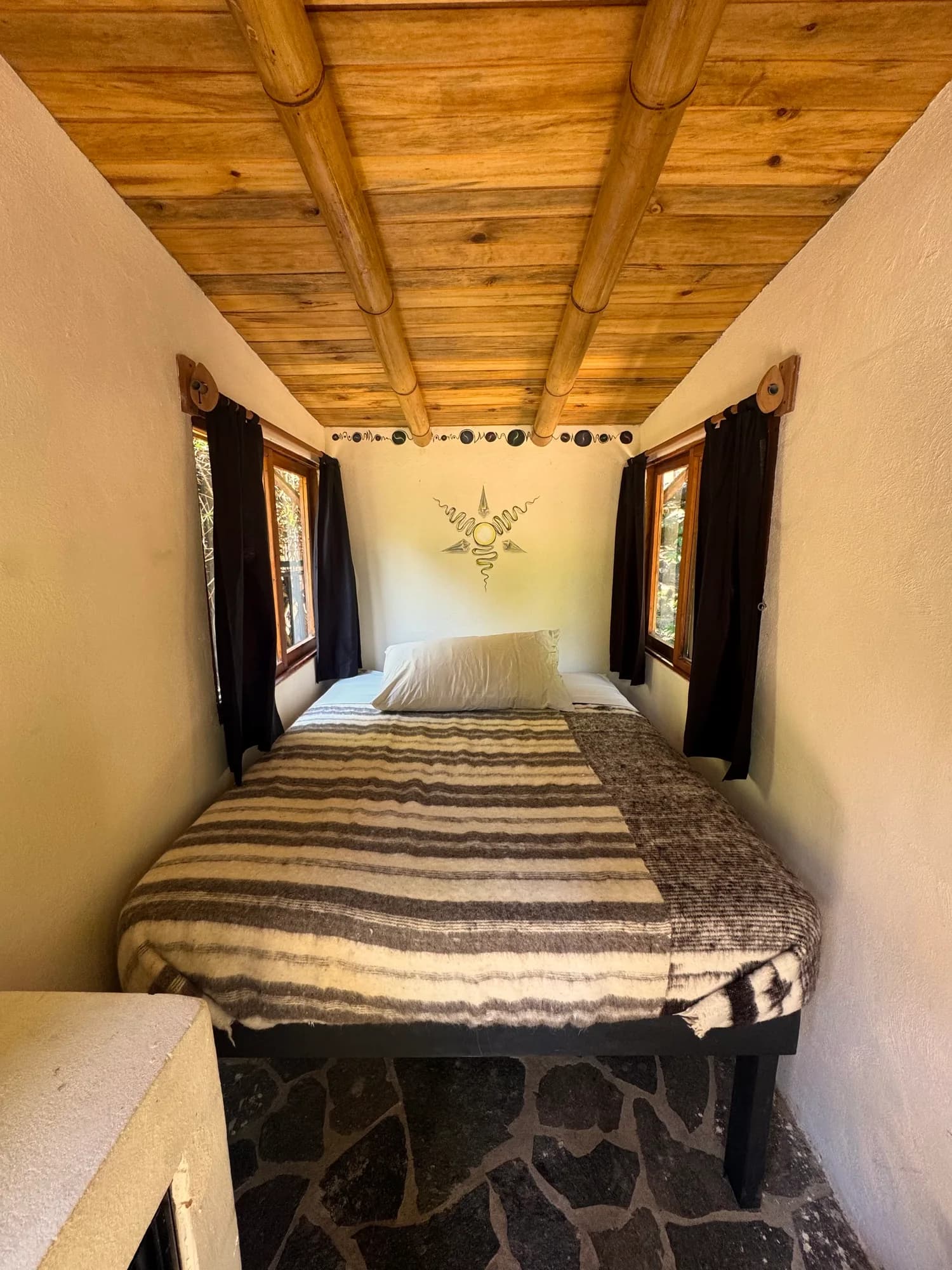 Private cabin bedroom with a wood ceiling and forest-facing windows