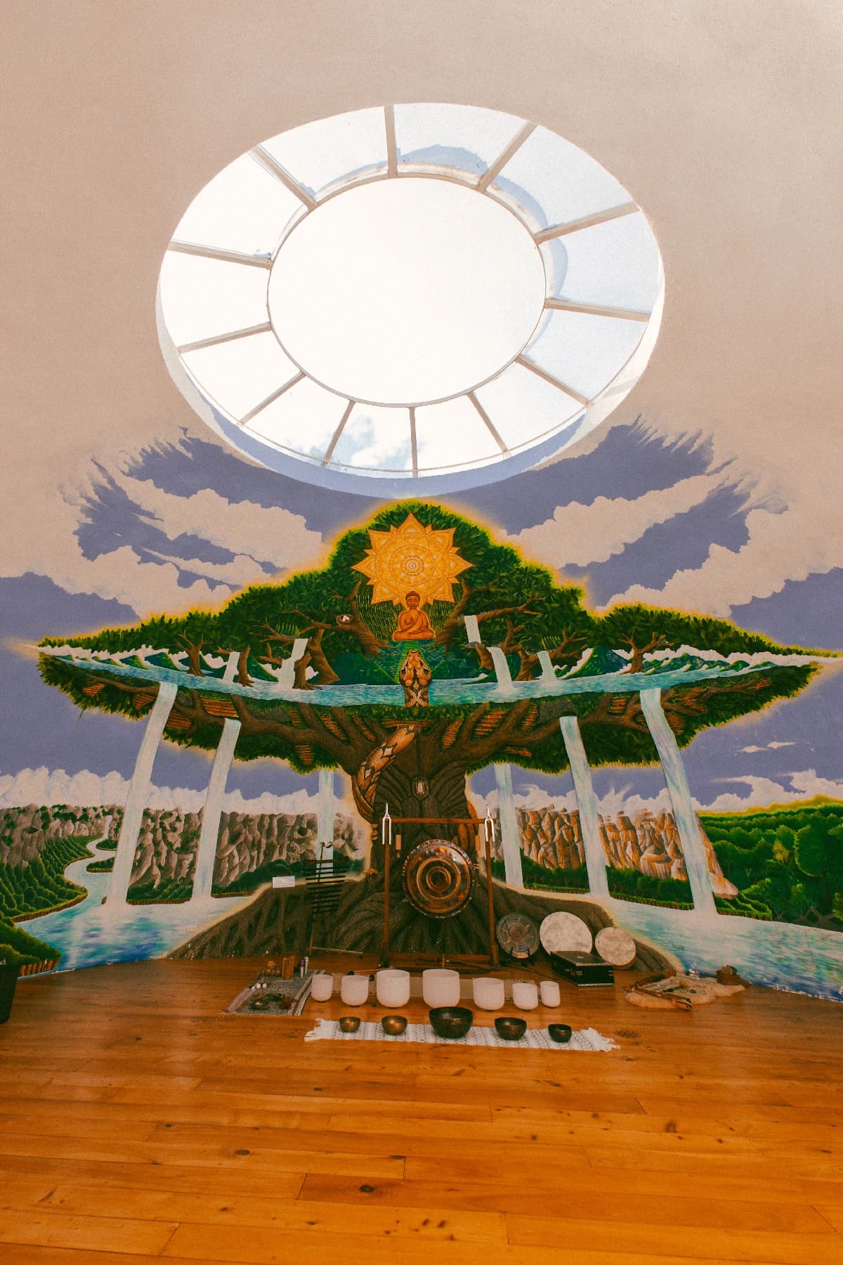 Sound bowls and a gong beneath the painted tree mural inside the Maestro Valley sound dome