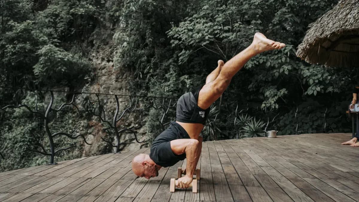 A retreat guest balancing upside down on exercise blocks on an outdoor jungle deck